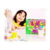 set-creativ-cu-slime-verde-utilizare Set creativ cu slime, fetiță în tricou galben întinde slime transparent cu bile pastelate, lângă cutia verde SLIME
