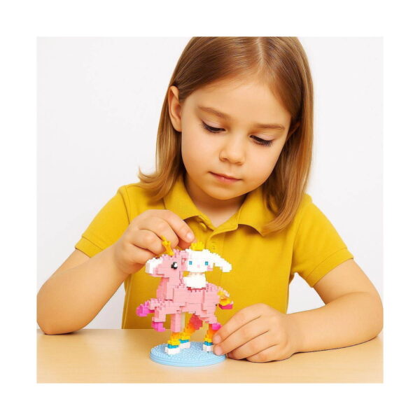 set-creativ-hello-kitty-utilizare-2 Set creativ Hello Kitty, fetiță fixând o piesă pe unicornul roz cu personaj alb cu coroană, pe bază cu curcubeu
