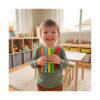 set-de-5-fidget-pop-tubes-mici-utilizare Set de 5 Fidget Pop Tubes mici, băiețel zâmbitor într-o cameră de joacă, ținând în mâini cinci tuburi mici, colorate