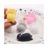 Set de 5 squishy pisicuță, o mână ține o pisicuță squishy galbenă deasupra unei farfurii albe pe care stau alte pisicuțe