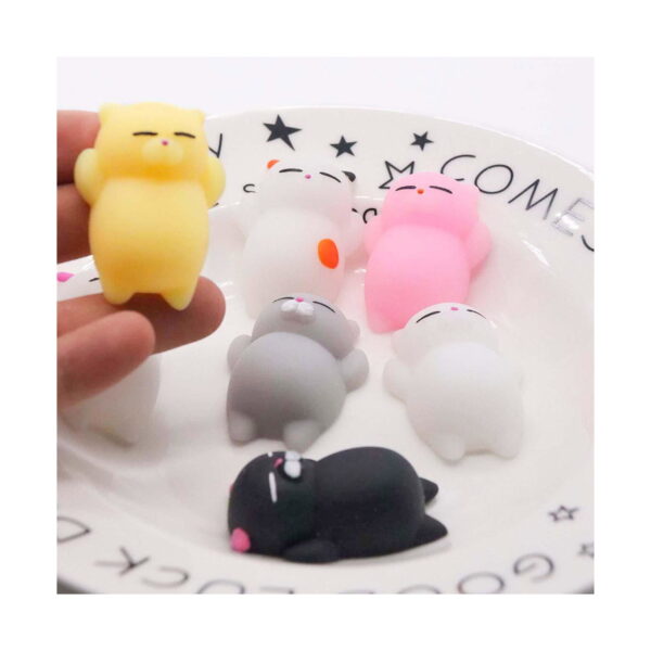 Set de 5 squishy pisicuță, o mână ține o pisicuță squishy galbenă deasupra unei farfurii albe pe care stau alte pisicuțe