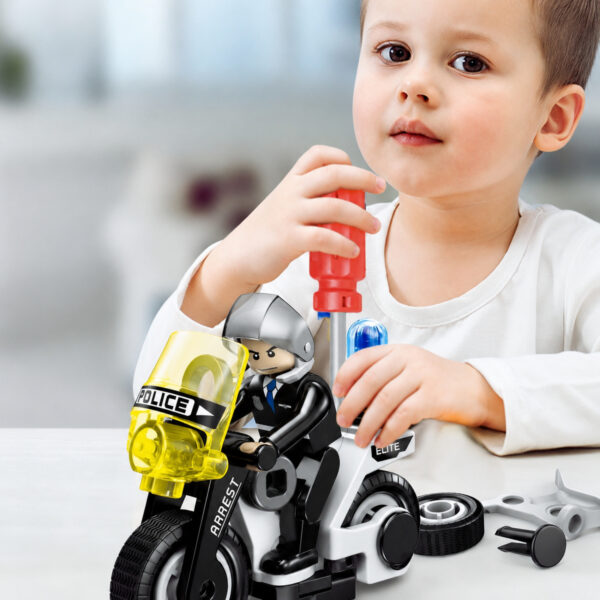 set-de-constructie-stem-politie-4-in-1-utilizare-2 Set de construcție STEM poliție 4 în 1, prim-plan cu un băiat care folosește o șurubelniță roșie la o motocicletă de poliție