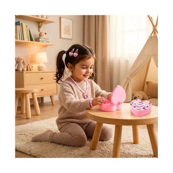 set-elsa-si-anna-disney-world-utilizare Set Elsa și Anna Disney World, fetiță așezată pe covor lângă o măsuță, cu cutia roz în formă de inimă deschisă; poartă