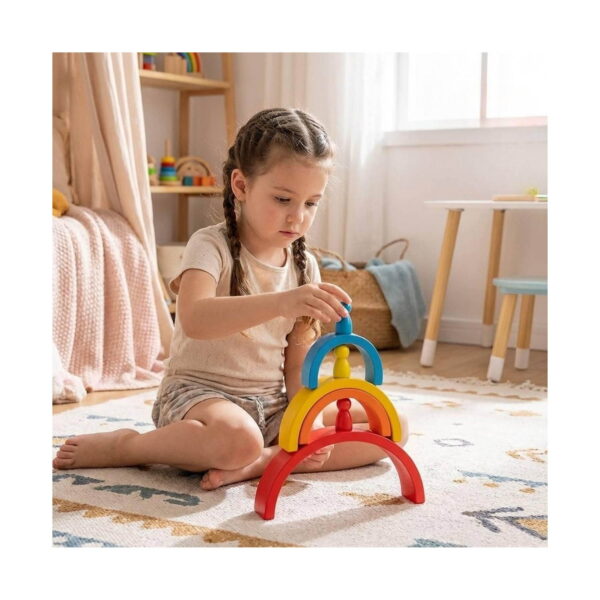 set-jucarii-educative-montessori-curcubeu-utilizare Set jucării educative Montessori curcubeu, fetiță cu codițe, așezată pe covor într-o cameră de copii