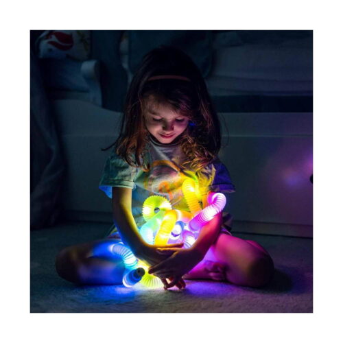 Set Paradis de vară, fetiță așezată pe podea în întuneric, ținând mai multe tuburi luminoase colorate