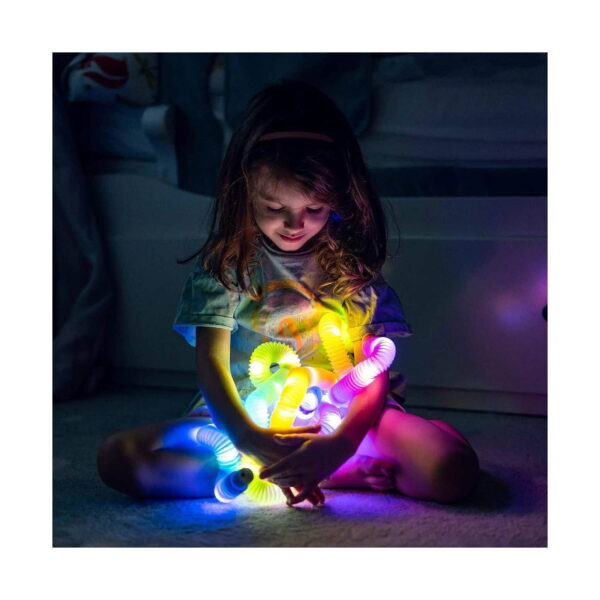 set-paradis-de-vara-utilizare Set Paradis de vară, fetiță așezată pe podea în întuneric, ținând mai multe tuburi luminoase colorate