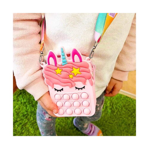 set-pop-it-unicorn-cu-geanta-si-accesorii-utilizare Set Pop It unicorn cu geantă și accesorii, copil care poartă pe umăr geanta Pop It unicorn roz, cu coamă roz, corn mentă