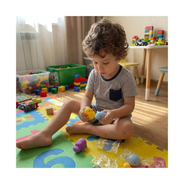set-senzorial-panda-si-prieteni-9-jucarii-utilizare-3 Set senzorial panda și Prieteni, băiat pe salteaua de joacă ținând o rățușcă galbenă și un animăluț albastru squishy