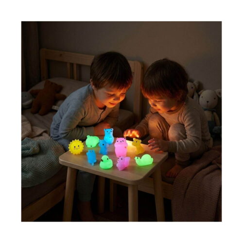 Set squishies luminoase, doi copii într-o cameră întunecată, la o măsuță, privind mai multe figurine squishy care strălucesc