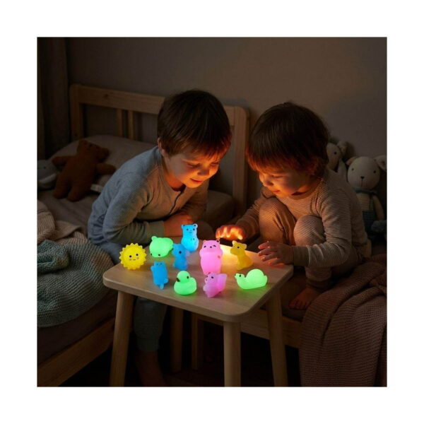 set-squishies-luminoase-jucarii-antistres-utilizare Set squishies luminoase, doi copii într-o cameră întunecată, la o măsuță, privind mai multe figurine squishy care strălucesc