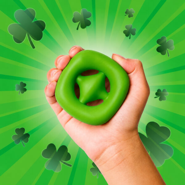 Snapperz multicolor din cauciuc, mână care strânge un Snapperz verde, pe un fundal verde cu trifoi