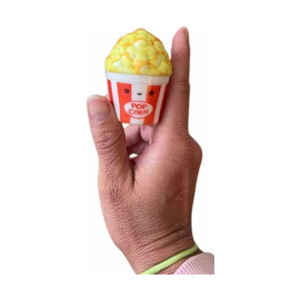 squishy-distractiv-in-forma-de-popcorn-3 Squishy distractiv în formă de popcorn, squishy-ul popcorn ținut între degete, cu fața zâmbitoare vizibilă
