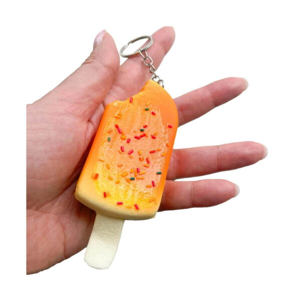 Squishy înghețată Bucuria copiilor, squishy portocalie așezată într-o palmă deschisă, cu inelul de chei atârnând