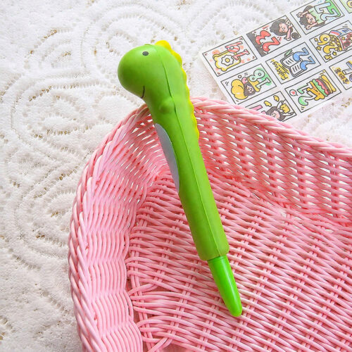 Pix squishy, cu cap de dinozaur verde, așezat pe un coșuleț roz împletit