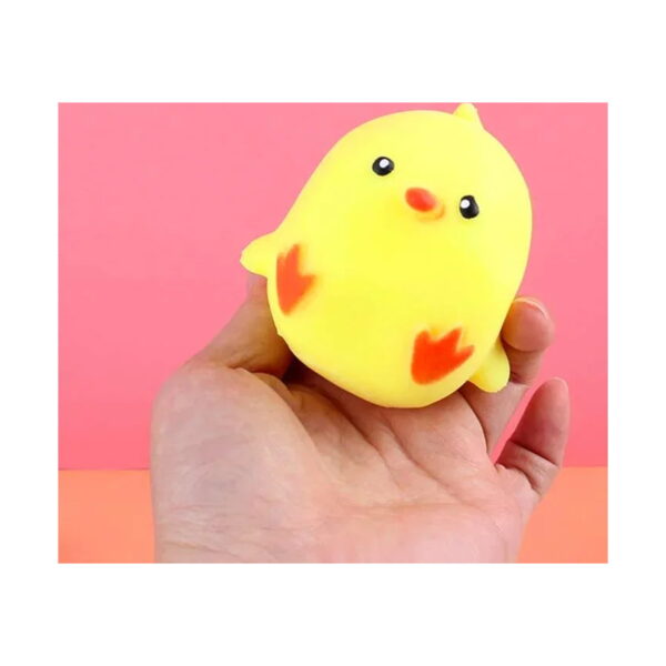 squishy-ratusca Squishy rățușcă, jucărie squishy galbenă în formă de pui de pasăre, cu cioc portocaliu ascuțit, ținută în palmă pe fundal roz